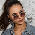 Close-up of oval metal sunglasses with purple gradient lenses and gold frames on model - Gold Frame Grey Pink Lens