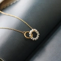 Elegante gouden titanium stalen ketting met in elkaar grijpende parel- en gedraaide ringen - Parel Dubbele Ring / Goud