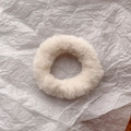 Close-up of soft beige faux rabbit fur scrunchie on textured paper background - Off-white