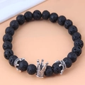 Macro view of black lava stone beads with a detailed silver crown charm accent - Crown