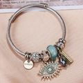 Macro detail of stainless steel charm bracelet with evil eye pendant on silk - Silver-Multicolor Beads