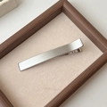 Primer plano de una pinza para el cabello de metal cepillado plateado en bandeja de terciopelo - Plateado