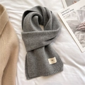 Detail of soft gray knitted scarf featuring a ribbed finish and a minimalist brand tag - Heather Grey