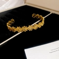 Detailopname van gouden bloemenarmband met fijne bloemblaadjes op zwart fluweel - Bloem / Goud