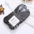 Detail of high-elastic black seamless hair ties on white fabric with a small bear decoration - 50 Pcs Bag / Black