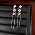 Vue détaillée des boucles d'oreilles fleurs argentées avec glands et zircons sur cuir noir - Argenté