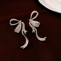 Eleganti orecchini a fiocco in argento con strass scintillanti su sfondo di velluto rosso - Orecchini a Fiocco Argento / Argento