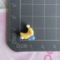 Macro view of a miniature yellow crescent moon resin accessory with a blue star on a grid mat - Moon Blue Star