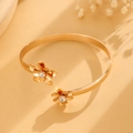 Dettaglio del bracciale rigido dorato con doppi fiori di cristallo e finitura lucida - Bracciale Aperto a Doppia Fioritura Oro (2828)