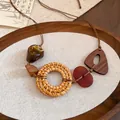 Bohemian rattan hoop and resin triangle pendant necklace on a rustic wooden tray - Necklace-Coffee