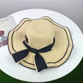 Détail d'un chapeau de paille beige avec bord ondulé, liseré noir et grand ruban - M (56-58cm) / Beige