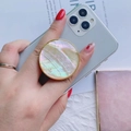 Soporte de nácar de abulón para móvil con borde dorado en un smartphone blanco - Agarre de Enchufe Plegable Redondo Dorado / Concha de Vieira Blanca