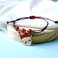 Detailed macro shot of braided Christmas bracelet with Santa charm and mini bell on wood - Santa with Glasses