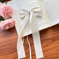 Elegant cream white satin ribbon hair bow clip with long streamers on wooden background - Beige