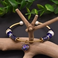 Golden pearl bracelet with blue cloisonne beads and round charms on a wooden branch - Gold Pandora Style Cloisonne
