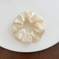 Close-up of a cream white silk scrunchie with soft satin luster on a ceramic plate - Large / Off-white