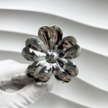 Gros plan sur la pince à cheveux fleur en métal argenté poli avec finition brillante - Fleur de chance / Argent
