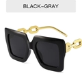 Gafas de sol cuadradas negras con lentes grises y patillas de cadena dorada en fondo blanco - Montura Negra Lente Gris