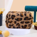 Detailed texture of brown leopard print plush makeup bag on a professional display stand - African Leopard