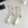 Milchweiße Strickstrümpfe mit Spitzenbündchen und zarter Schleifenstickerei im Detail - Beige