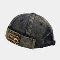 Dettaglio del berretto docker in denim consumato con lavaggio vintage e toppa ricamata - Blu scuro nerastro