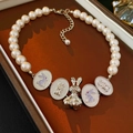 Close-up of pearl necklace featuring 3D rabbit charms and engraved oval metal plates - Necklace / Silver