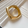 Macro detail of polished gold wavy square bangle on a beige striped display tray - Gold - Round Square Geometric