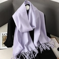 Dettaglio di morbida sciarpa lilla in finta cashmere con frange su abbigliamento nero - viola lilla