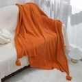 Bright orange knit throw blanket with wave texture and tassels on white sofa - Orange Red