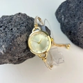 Detail of gold bracelet watch for women with diamond-encrusted bezel on dark rocks - Gold
