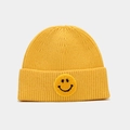 Detail van een gele gebreide muts met een zwarte smiley-gezicht patch erop - Geel