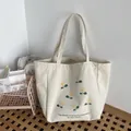 Detail view of the metal snap button closure and yellow floral print on canvas tote - Yellow Flower Green Leaf Pattern