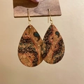 Dettaglio di orecchini vintage in pelle con motivo floreale bohémien su supporto in legno - Motivo Floreale Marrone
