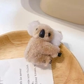 Cute plush koala hair clip in light brown with fluffy white ears on a wood surface - Khaki Koala