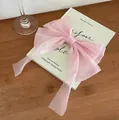 Elegante lazo grande de organza rosa con cintas largas sobre un libro decorativo - Rosa