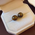 Macro view of round tiger eye stone stud earrings in a beige velvet jewelry box - Coffee (10mm)
