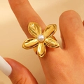 Detail of a golden flower ring featuring textured petals and a pearl center on a finger - 3D Pearl Floral (10881)