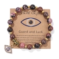 Macro detail of natural stone beaded bracelet featuring a gold evil eye charm pendant - 19cm / Rhodonite with Black Lines