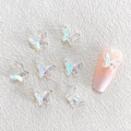 Macro detail of 3D iridescent resin butterfly charms for nail art on white background - Aurora White