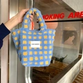 Detail der blau-gelb karierten Lammwoll-Tasche mit gewebtem Markenetikett auf der Front - Blau Kariert