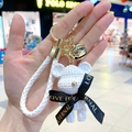 Detalle de llavero de oso blanco con campana dorada y correa tejida para bolso - Oso / Oso Blanco