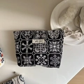 Detalle de neceser de lona negra vintage con bordados florales y etiqueta de diseño retro - Bordado de Mariposa y Copo de Nieve en Fondo Negro