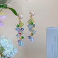 Détail de boucles d'oreilles bohèmes avec fleurs en résine pastel et glands en cristal - Pétales Colorés (12#)