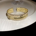 Makroaufnahme der vergoldeten breiten Manschette mit Zirkonia und Wabenmuster - Gold
