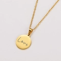 Primer plano de un colgante redondo de oro de 18k con grabado Love y cadena de oro fino - Dorado Love