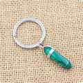Close-up of hexagonal green malachite stone pendant with silver key ring on linen fabric - Malachite