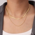 Detail of double-layer golden snake bone necklace worn over a gray suit and white shirt - Round Snake Layered Necklace