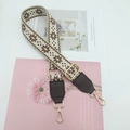 Detail of ethnic embroidery bag strap with gold metal hooks on a magazine background - Coffee with Coffee Leather