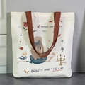 Cream canvas tote bag with woven brown handles and artistic hand-drawn cat illustration - Princess and Cat