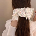 Floral oversized bow hair scrunchie with pink blossoms and cream ribbons on a model - Pink Fence Floral